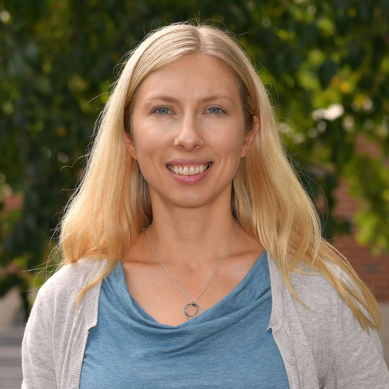 Image of Jessie Knowlton, directly facing the camera, and wearing a blue shirt and grey cardigan.