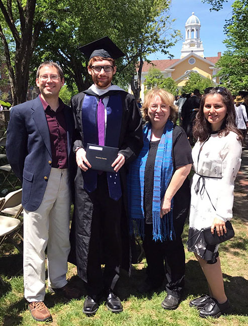 Student and family posed with professor at Graduation, May 2017